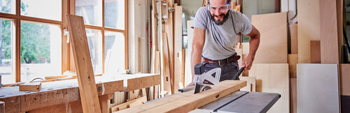 A man cuts a board in two parts with a table saw