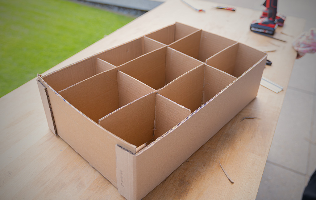 Kartonbox mit mehreren Fächern steht fertig zusammengebaut auf einem Tisch.