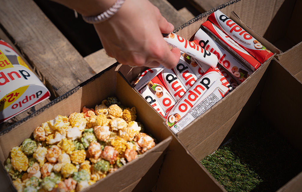 Hand legt verpackte Snacks und Popcorn in Fächer einer Kartonbox.