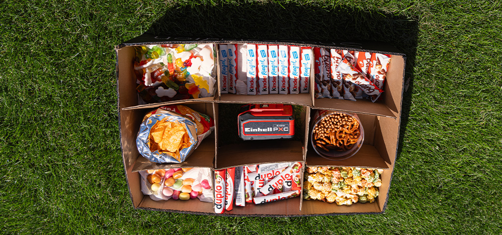 Draufsicht auf Snackbox mit Süßigkeiten, Chips und Brezeln in mehreren Fächern.