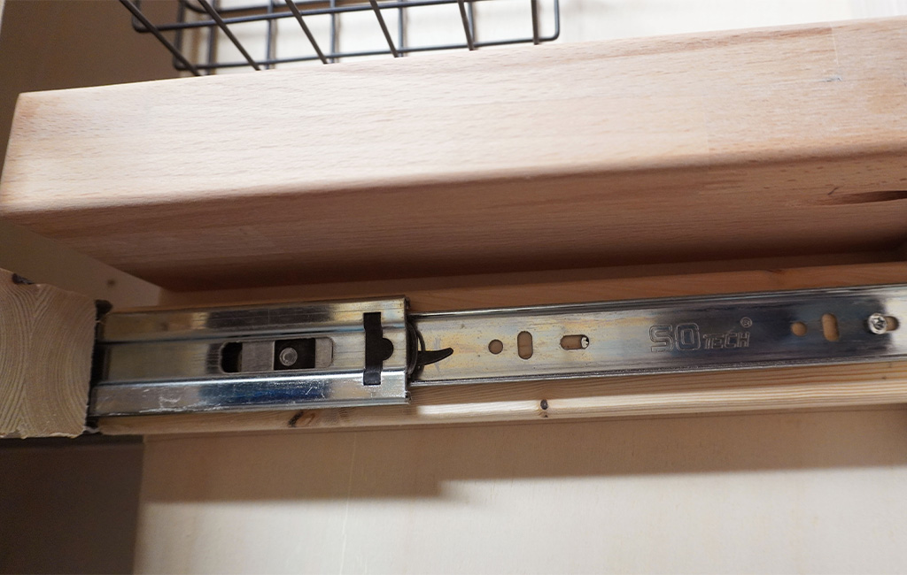 Ausziehbarer Korb in Holzrahmen auf Metallschiene