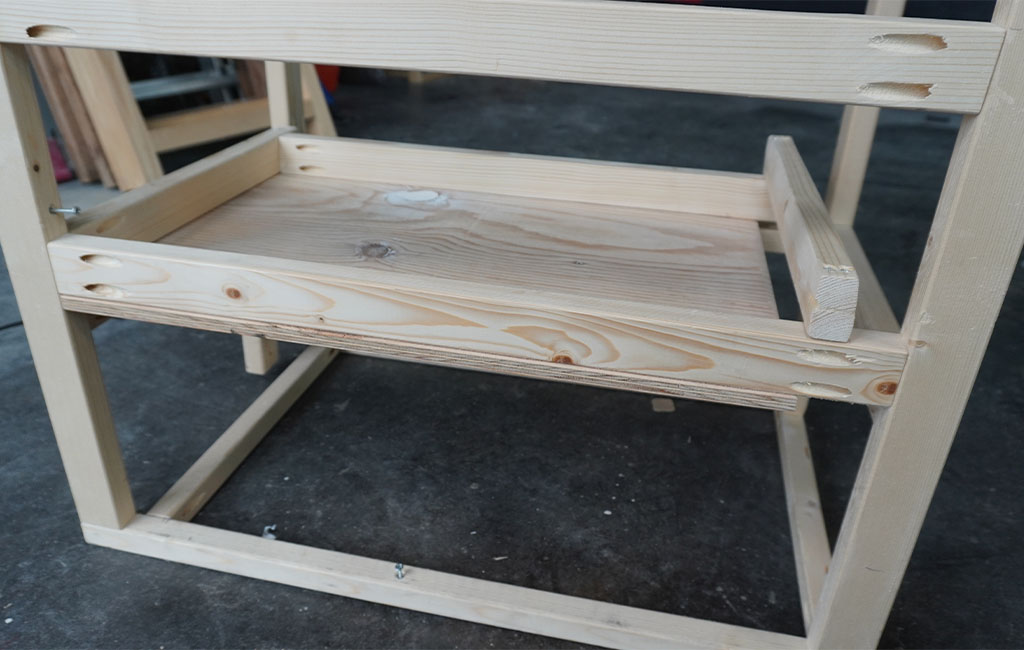 Holzkonstruktion mit eingesetztem Regalbrett, Taschenlochbohrungen sind deutlich sichtbar.