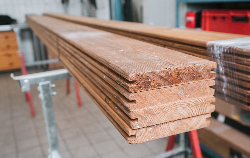 Several stacks of planed tongue-and-groove wooden slats on sawhorses in a workshop.
