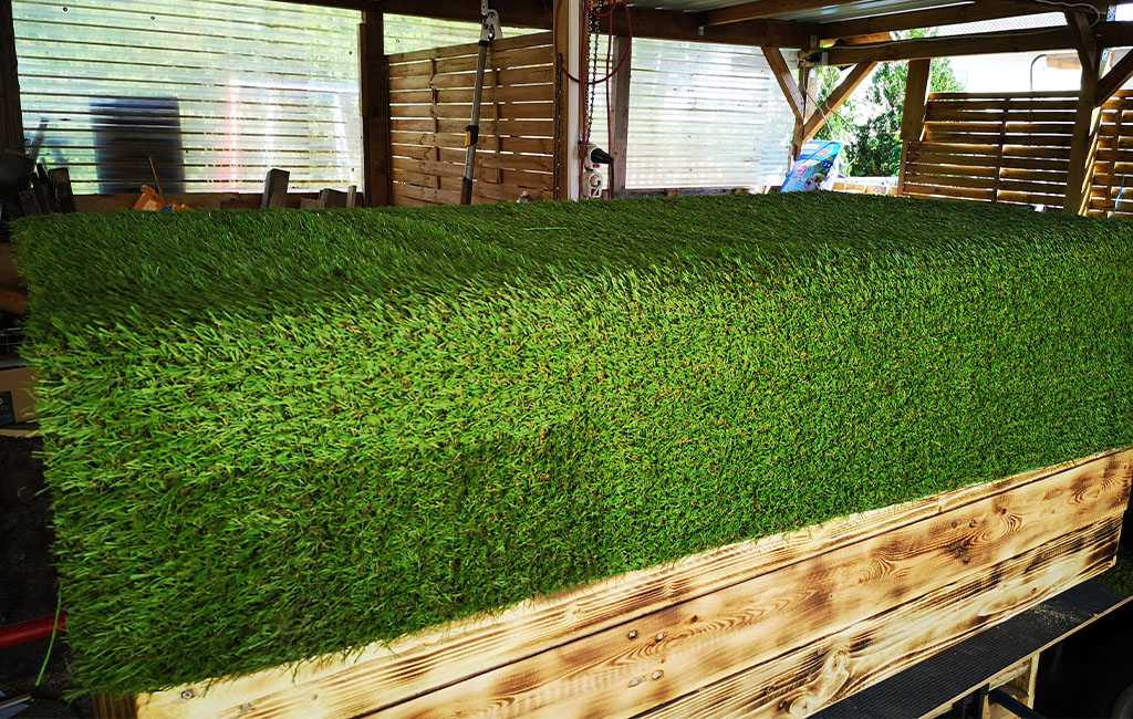 Close-up of the wooden chest with a closed lid. The lid is covered with green artificial grass.