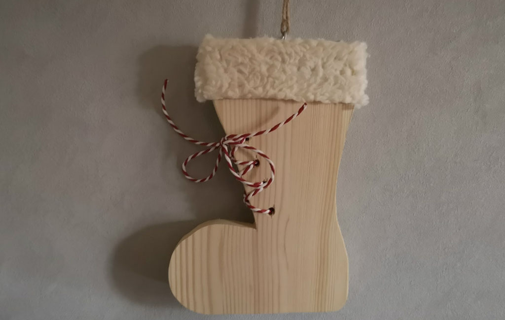 Handgefertigte Weihnachtsstrumpf-Dekoration aus Holz mit weichem Stoffbund und dekorativer Schnur.