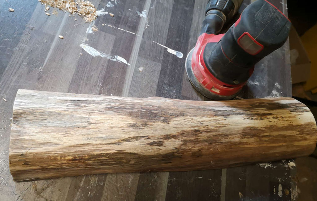 Holzstamm wird geschliffen, um ihn für eine DIY-Dekoration vorzubereiten.
