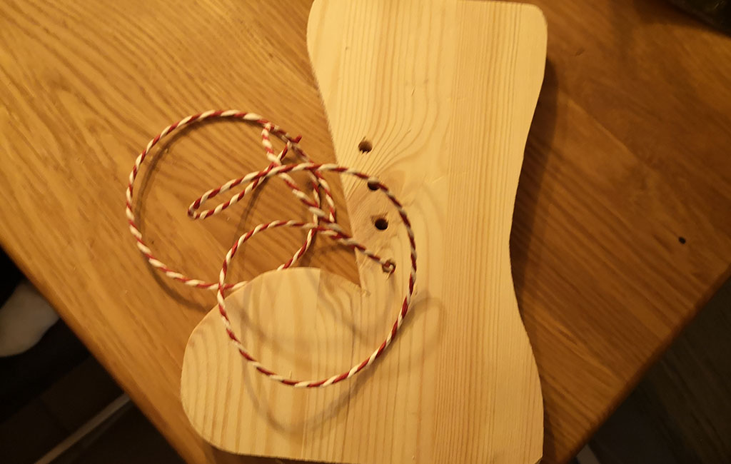 Dekorative Schnur wird an einer Holzschuh-Dekoration befestigt.