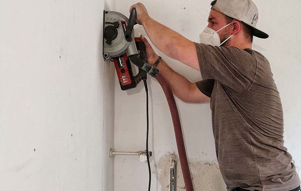 Person attaches a drill guide to a wall and aligns it for drilling.