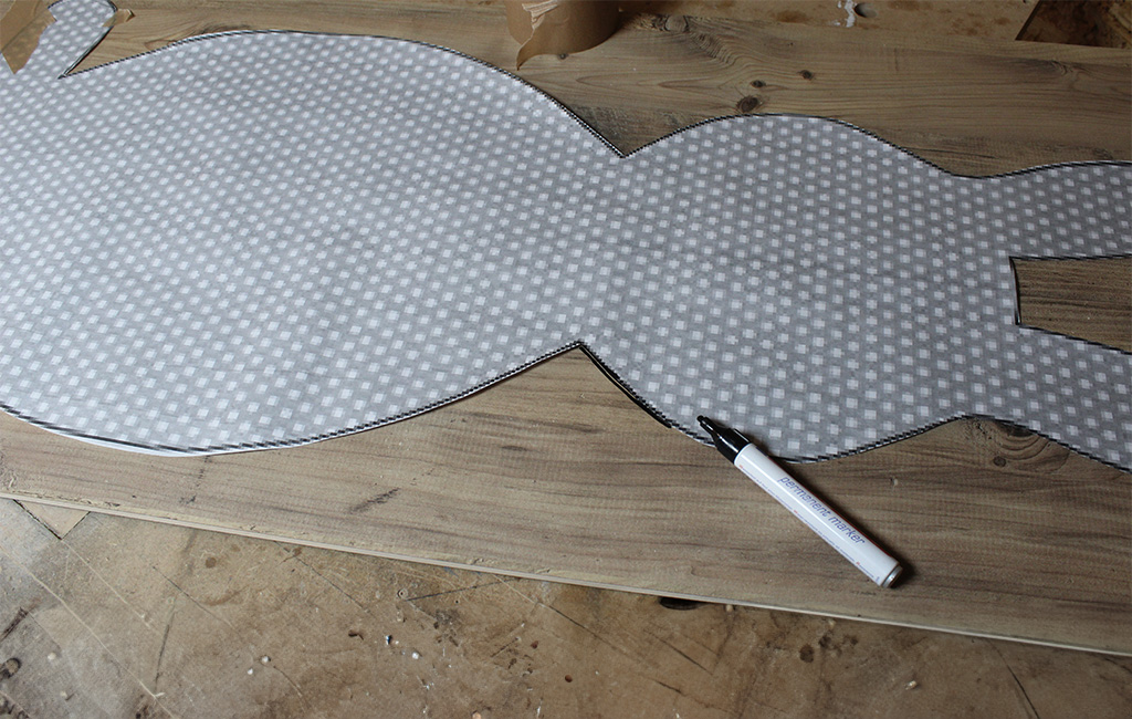 Bunny-shaped fabric template lies on a wooden board, with a black marker beside it.