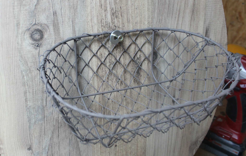 Wire basket mounted on a wooden board.