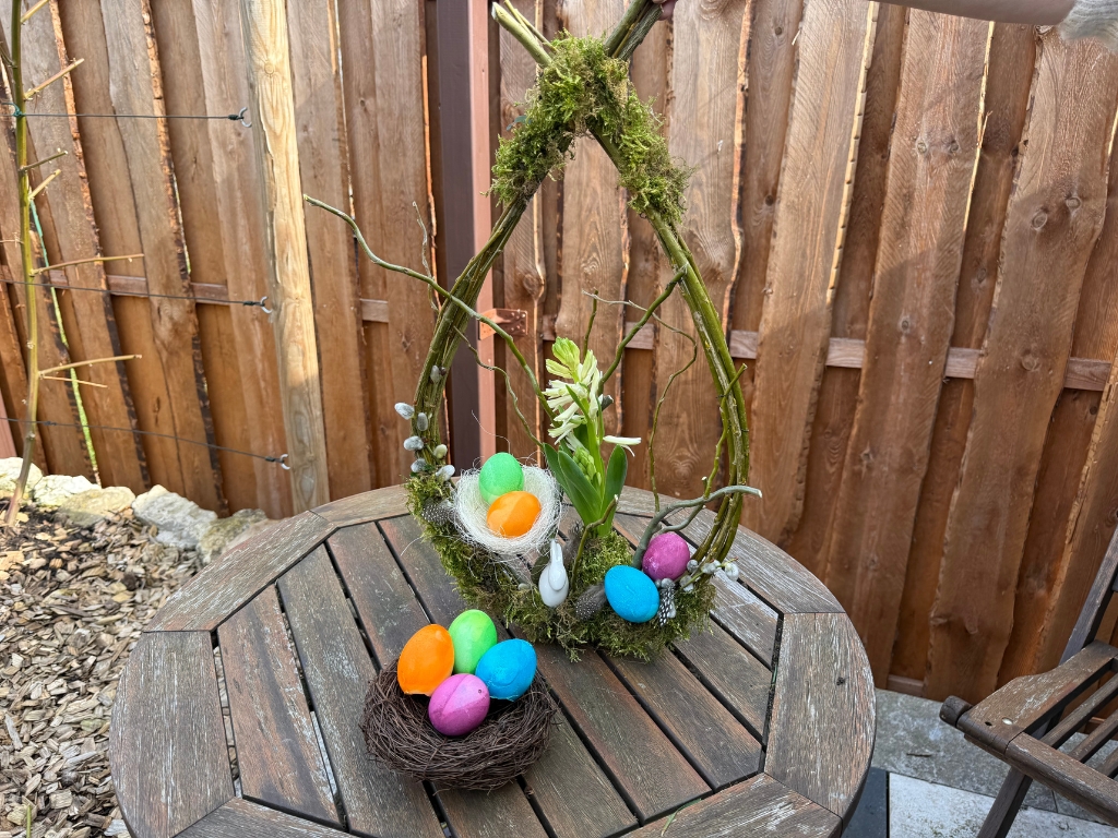 Close-up of the Easter wreath with colorful eggs, moss and flowers.
