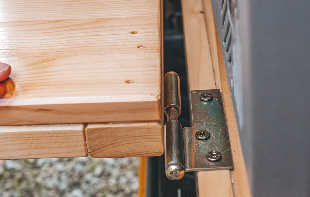 Close-up of a metal hinge connecting two wooden boards.