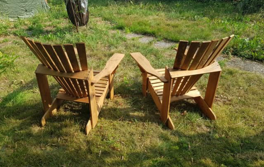 Two homemade wooden garden chairs stand side by side on a lawn.
