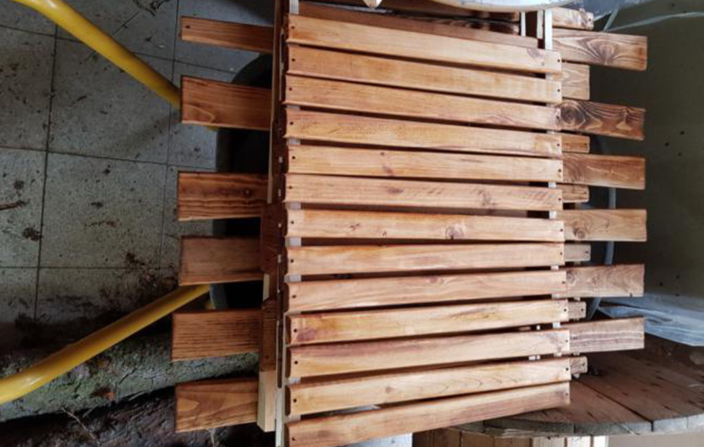 Several wooden slats are stacked on a workbench, ready for assembly.