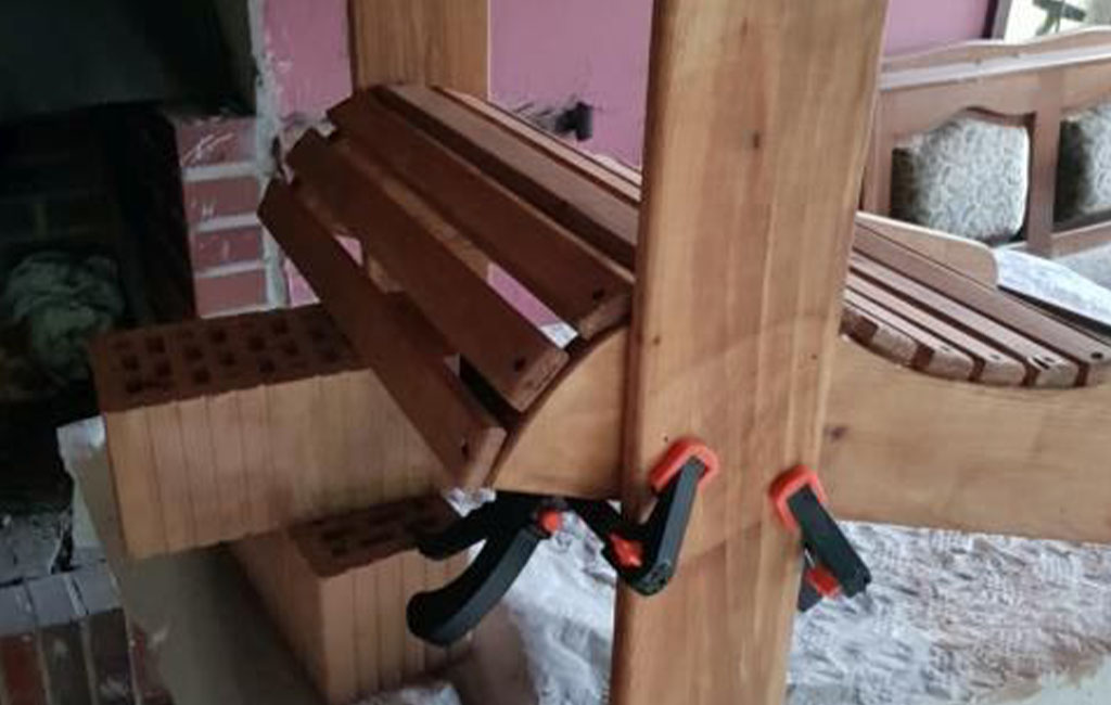 A garden chair is fixed with clamps, with the seat slats clearly visible.