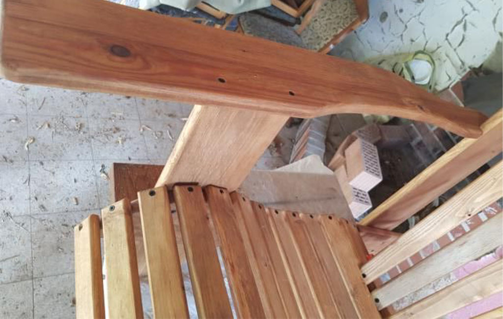 The curved armrest of a wooden chair is seen from above and already attached.