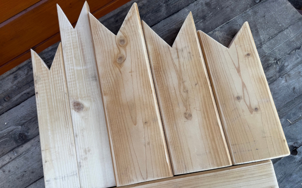 Mehrere zugeschnittene Holzbretter mit spitzen Enden liegen nebeneinander.