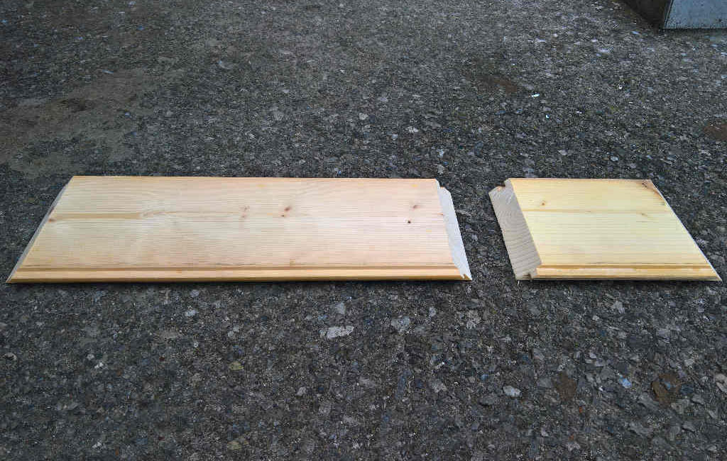 Two cut wooden boards with beveled edges lying on the ground.