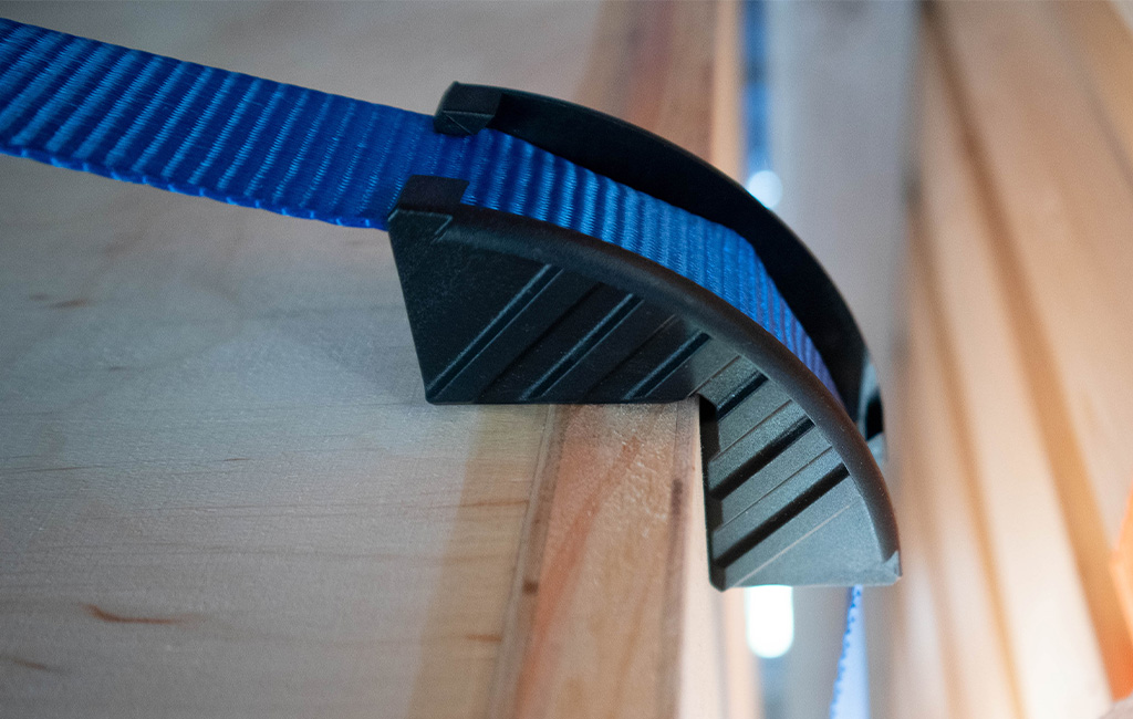 Close-up of a blue tension strap with black mount attached to a wooden panel.