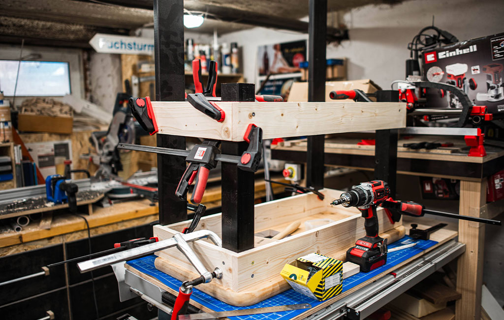 The wooden frame of the mud kitchen is clamped in place and screwed together.
