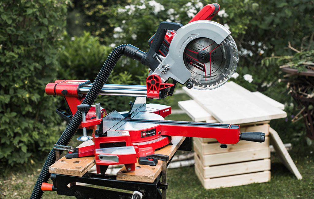 An Einhell sliding mitre saw is set up and ready for use on a workbench in the garden.