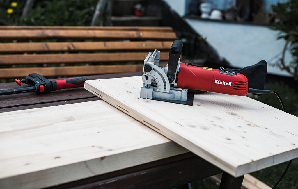 An Einhell biscuit joiner rests on a wooden board, ready for use.