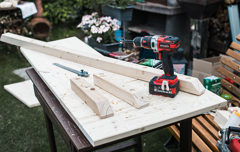 Cut wooden beams and an Einhell cordless drill are placed on a work table.
