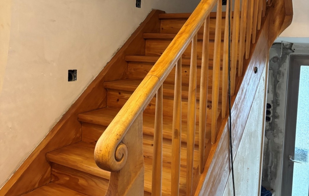 Geschliffene Holztreppe mit Geländer im Innenbereich während der Renovierung.