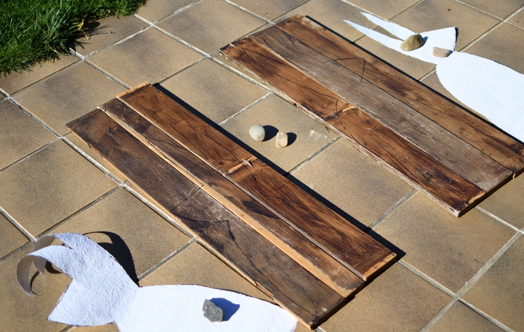 Mehrere Holzplatten mit aufgezeichneten Hasenformen liegen auf einer Terrasse bereit zur Bearbeitung.