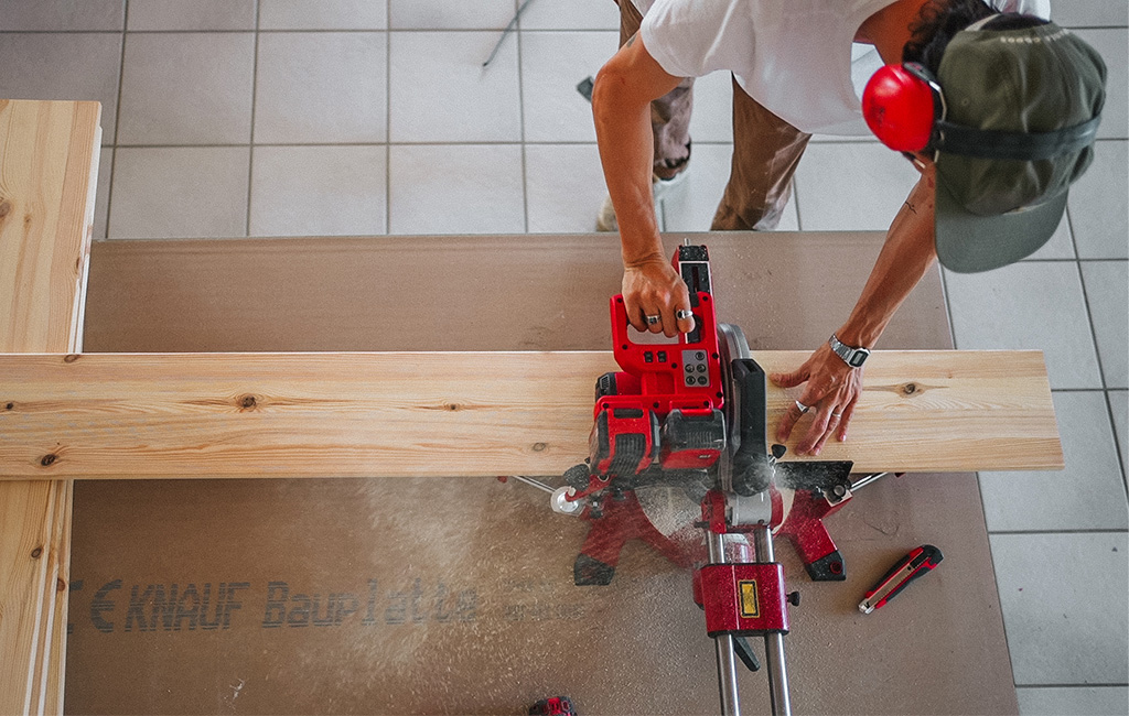 A miter saw is used to cut a wooden board precisely for the beach chair.