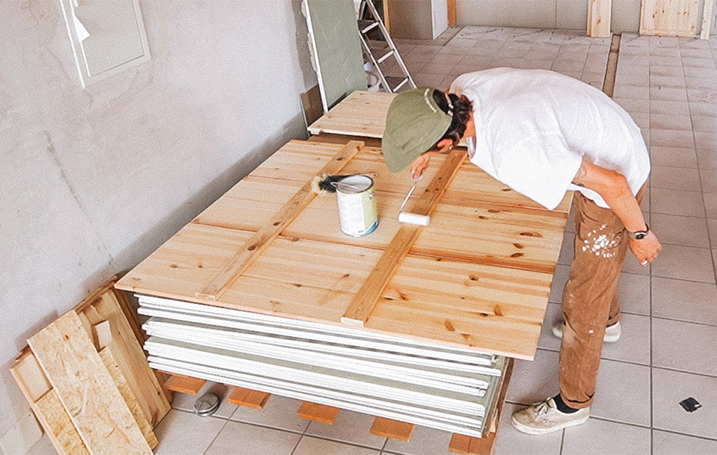 A man paints wooden boards for building a wooden beach chair.