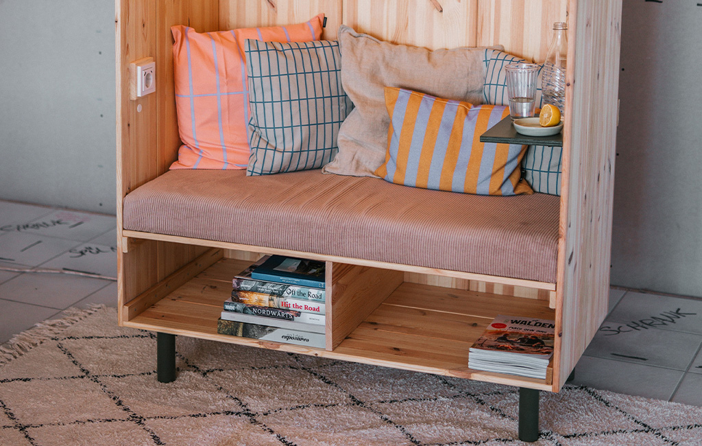 Close-up of the wooden beach chair with cushions, a small tray and books on the bottom shelf.