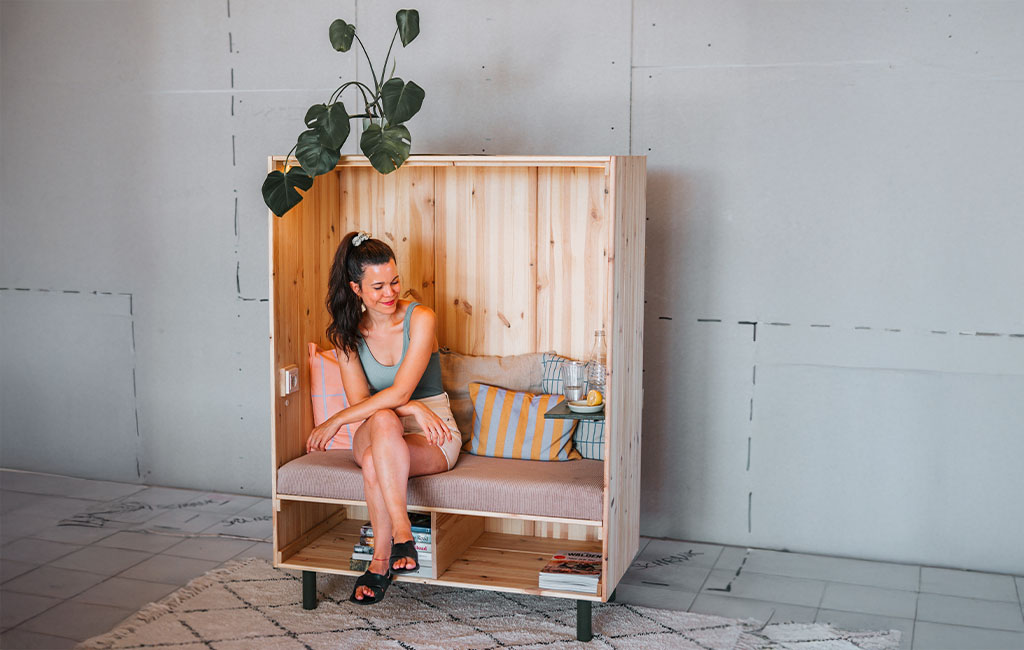 A woman sits relaxed in the finished wooden beach chair and smiles.