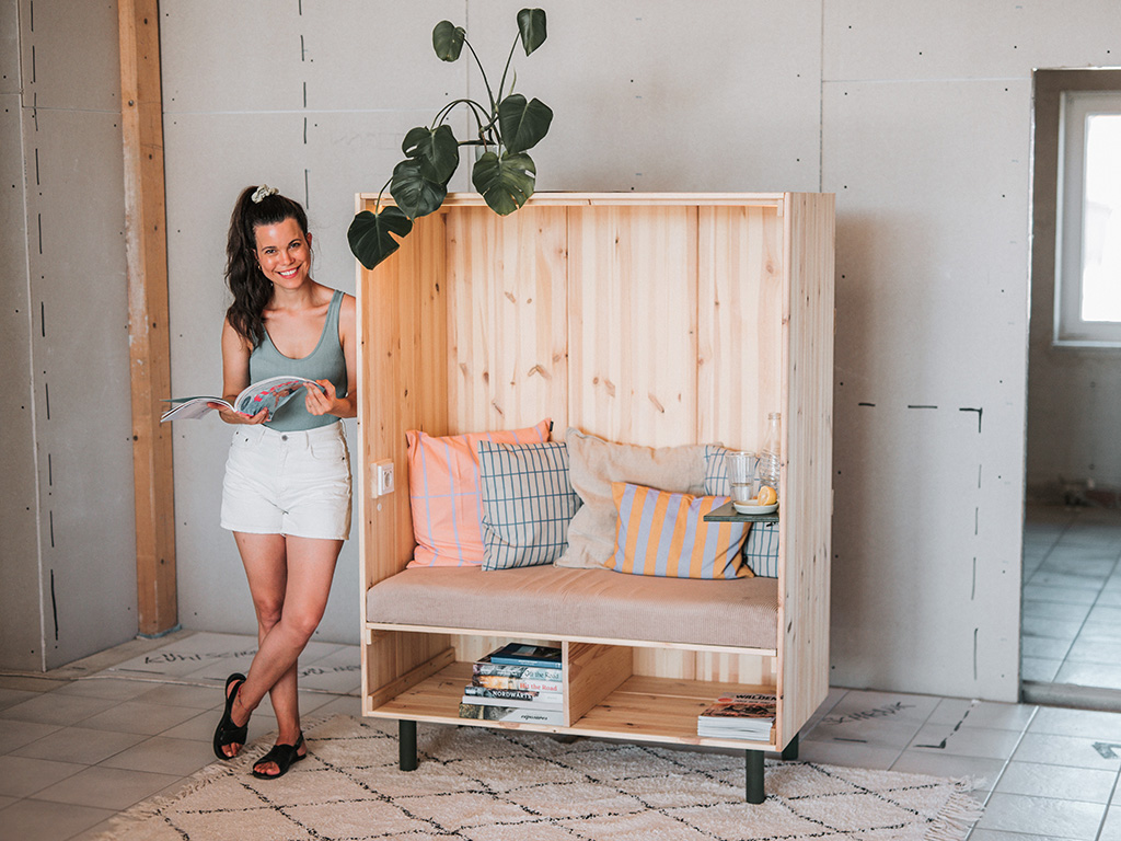 A woman sits relaxed in the finished wooden beach chair and smiles.