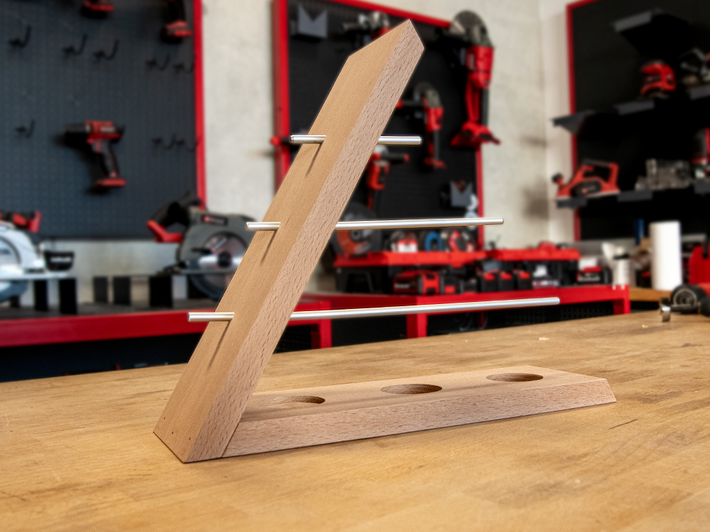 A slanted wooden jewellery stand with four metal rods and three round holes in the base.