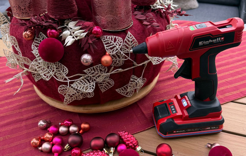 The Einhell cordless hot glue gun TE-CG 18 Li stands next to the Advent wreath, baubles ready for decorating.