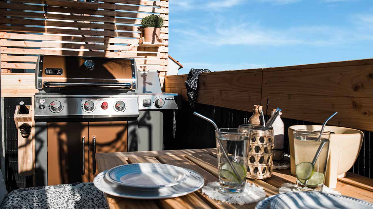 A laid table and a barbecue on a terrace.