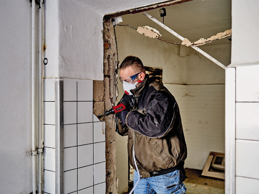a man uses a demolition hammer on the wall