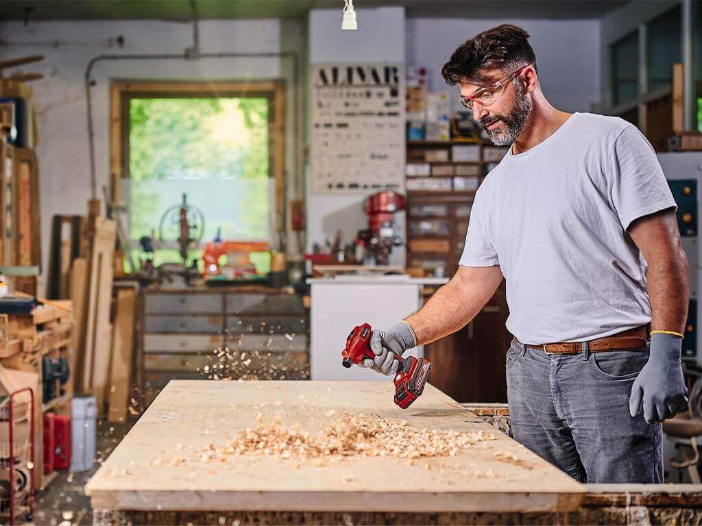 A man blows his workbench clean with the Einhell cordless air pump.