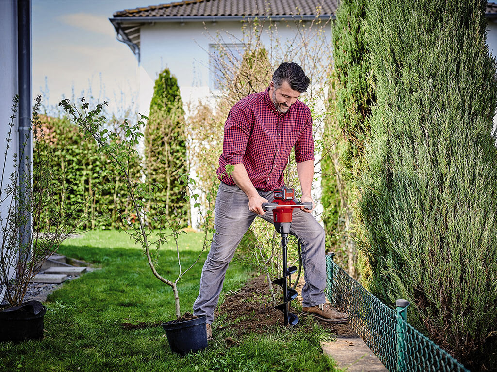 a man drills a hole with an Einhell earth drill