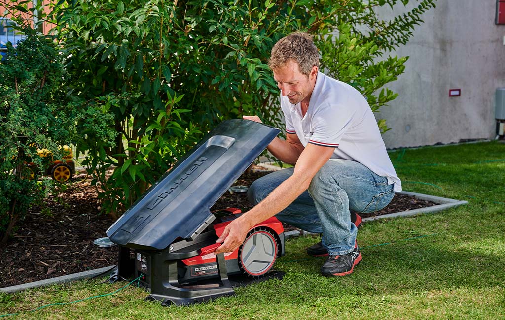 Ein Mann montiert eine Mähroboter-Garage in seinem Garten.