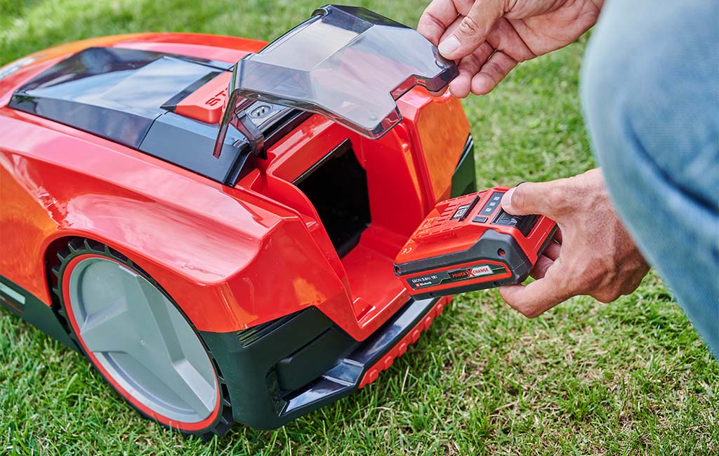 Ein Akku wird in einen Mähroboter gesteckt.