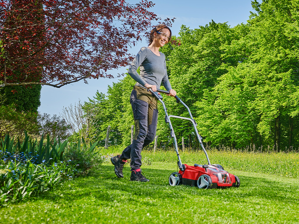 A woman with a cordless lawn aerator from Einhell during lawn care.