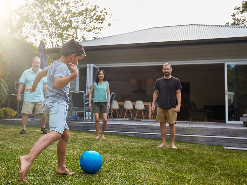 three adults play football tih a child