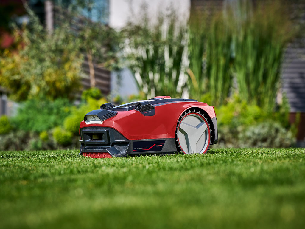 Ein Einhell Mähroboter auf einem gesunden, grünen Rasen im Garten