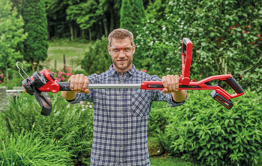 a man is holding a Einhell cordless lawn trimmer