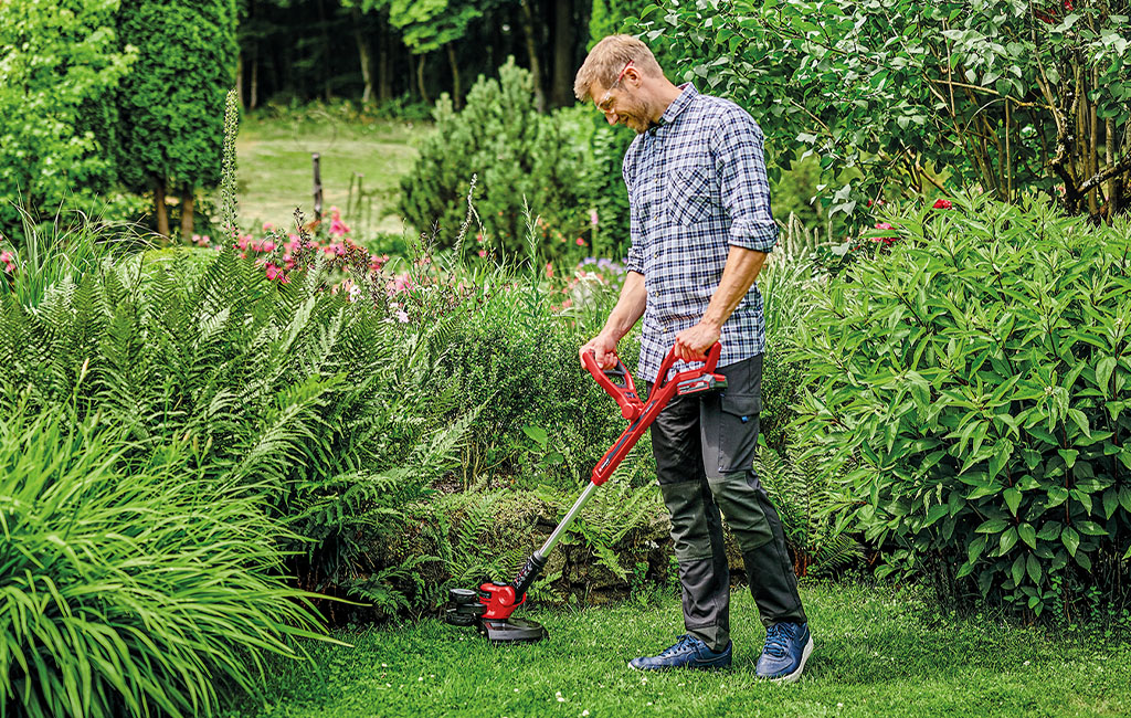a man is trimming the lawn with a Einhell cordless lawn trimmer