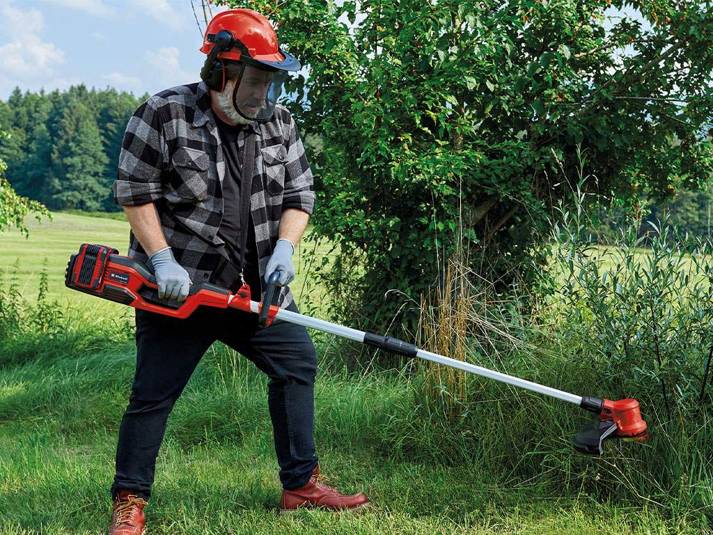 A man mows the grass with a brush cutter