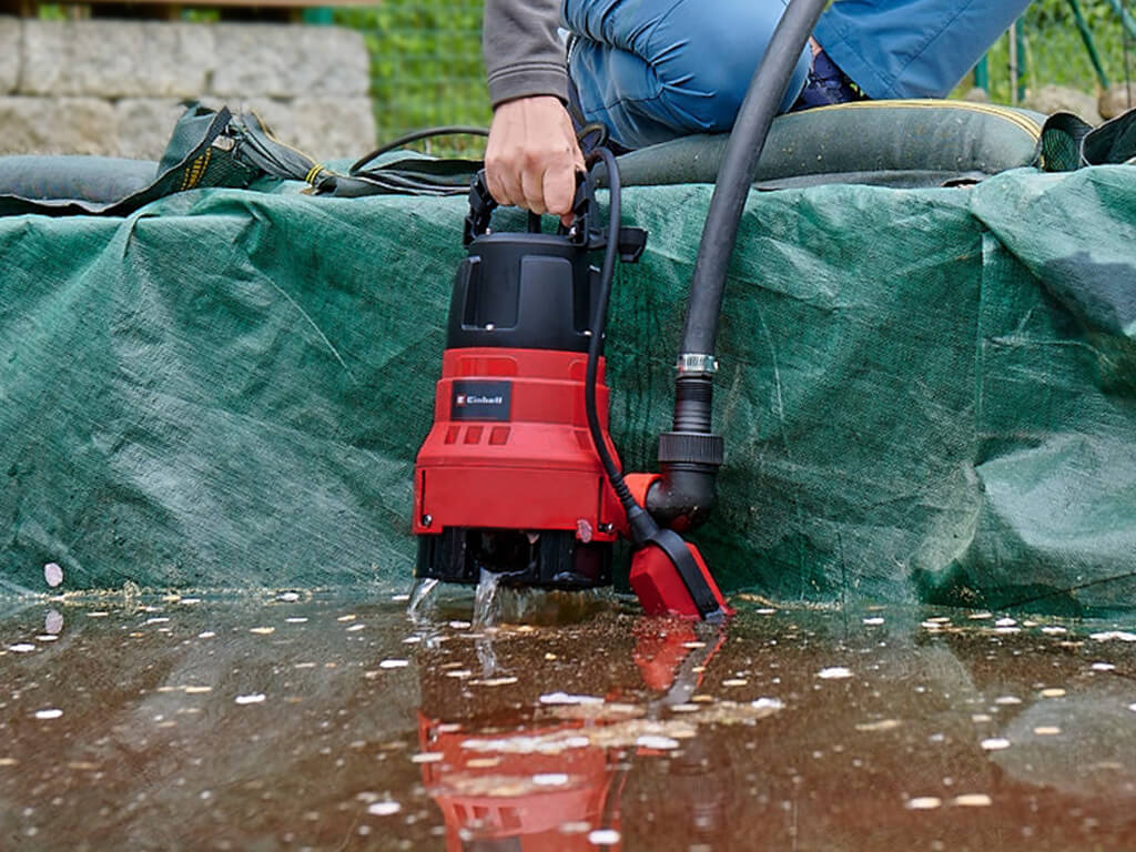 An Einhell dirty water pump is pulled out of dirty water.