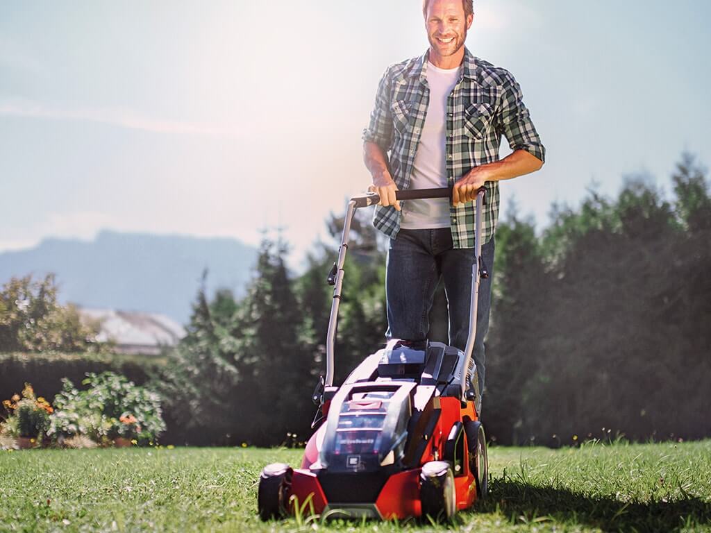 a man mows the lawn with a lawnmower